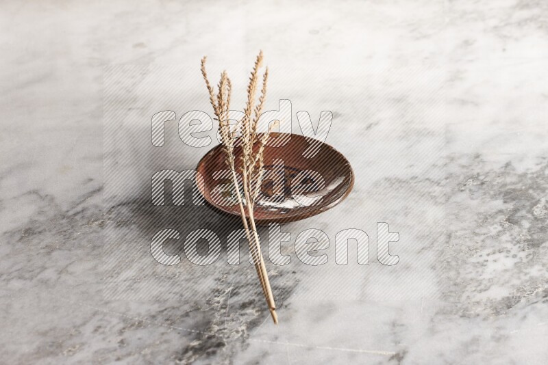 Wheat stalks on decorative pottery plate on grey marble background
