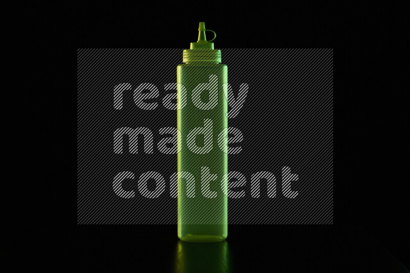 A squeeze bottle with colored rim light against black background