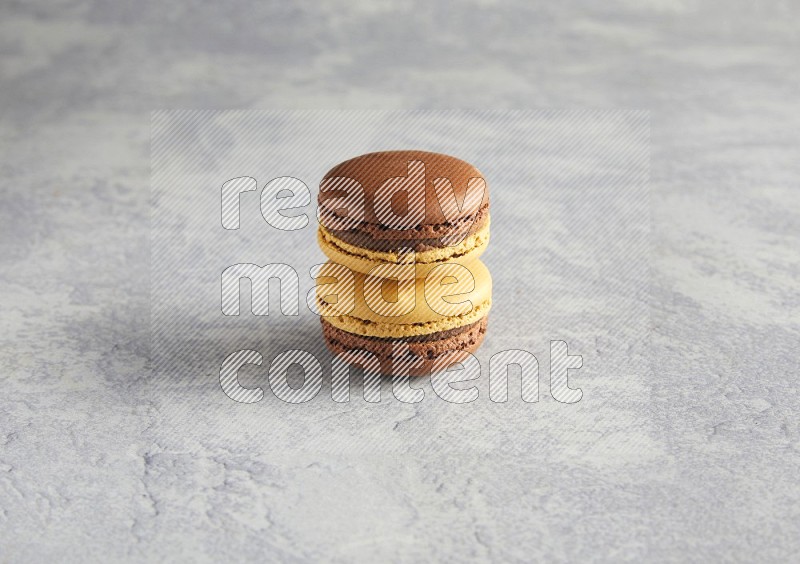 45º Shot of two Yellow and Brown Chai Latte macarons r on white  marble background