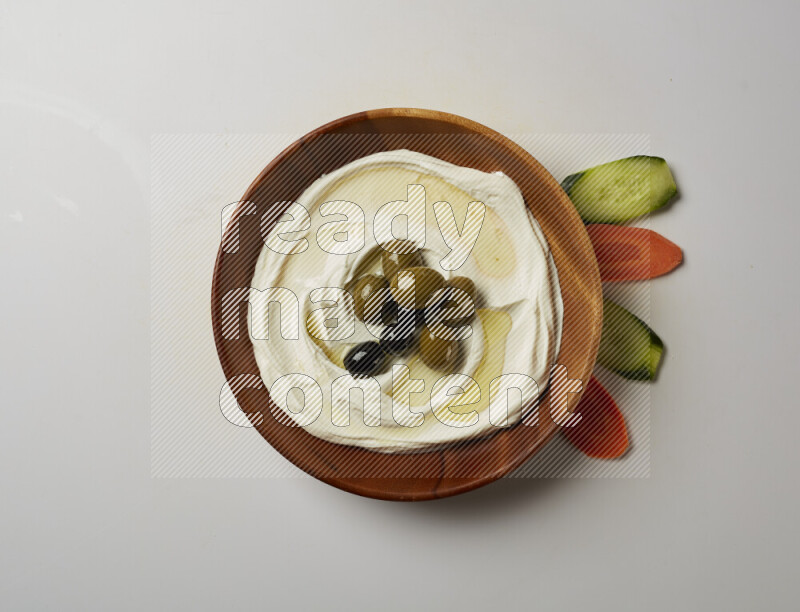 Lebnah garnished with whole olives in a wooden plate on a white background