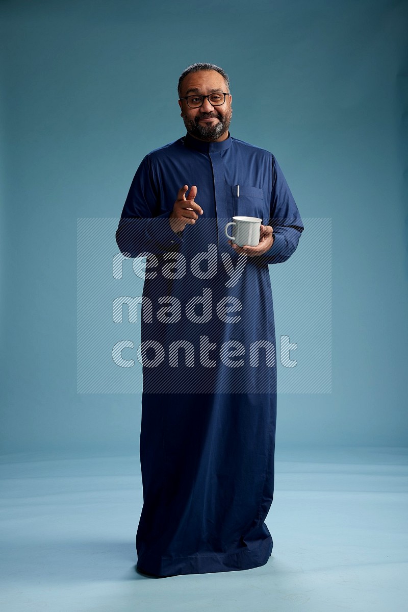 Saudi Man without shimag Standing drinking coffee on blue background