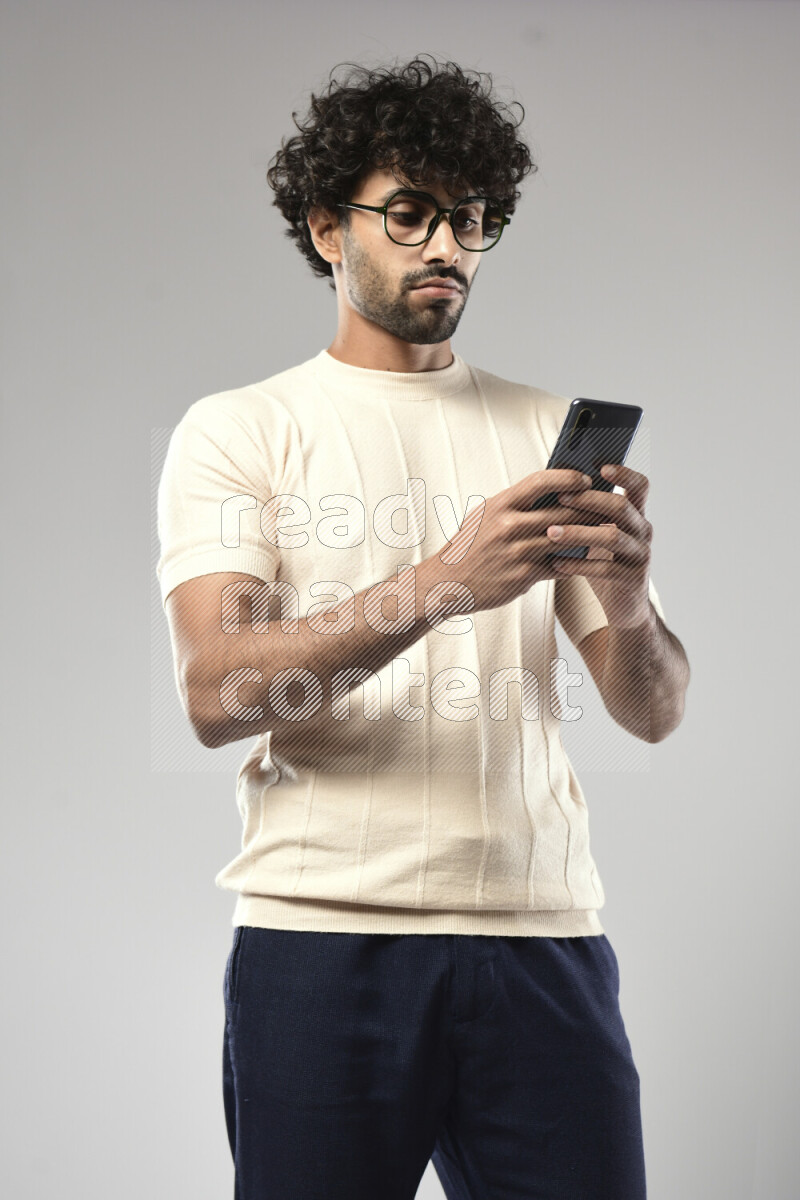 A man wearing casual standing and texting on the phone on white background