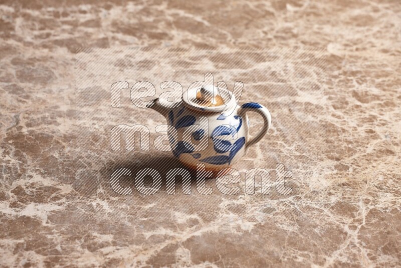 A pottery teapot on beige marble background
