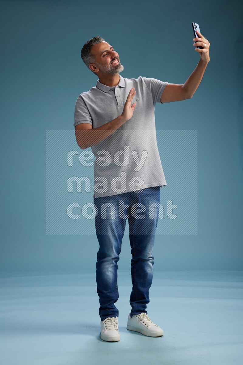 Man Standing taking selfie on blue background
