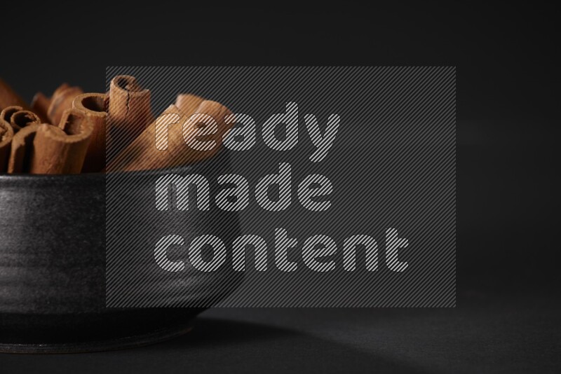 أعواد القرفة في وعاء فخاري أسود علي خلفية سوداء