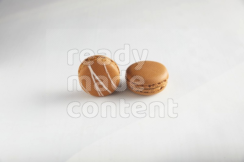 45º Shot of of two assorted Brown Irish Cream, and Brown Maple Taffy macarons  on white background