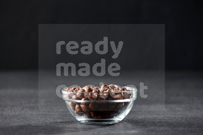 A glass bowl full of peeled hazelnuts on a black background in different angles