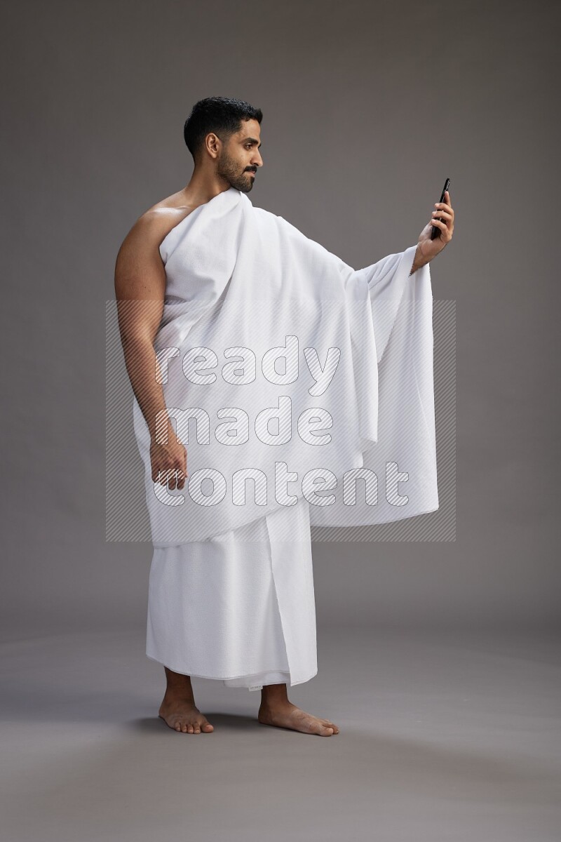 A man wearing Ehram Standing taking selfie on gray background