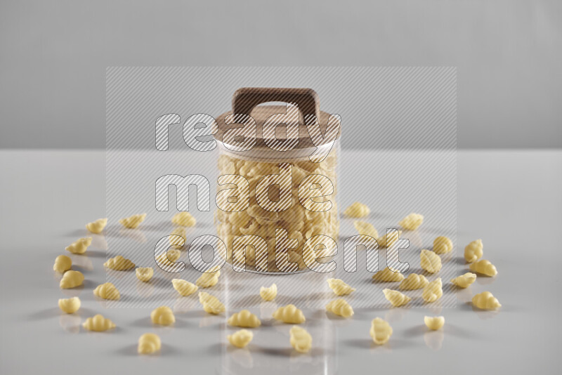 Raw pasta in a glass jar on light grey background