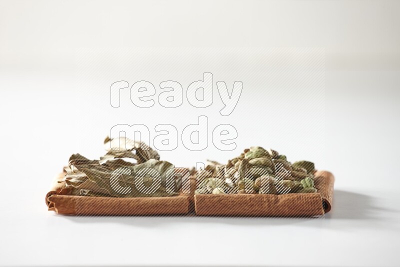 2 squares of cinnamon sticks full of cardamom and bay laurel leaves on white flooring