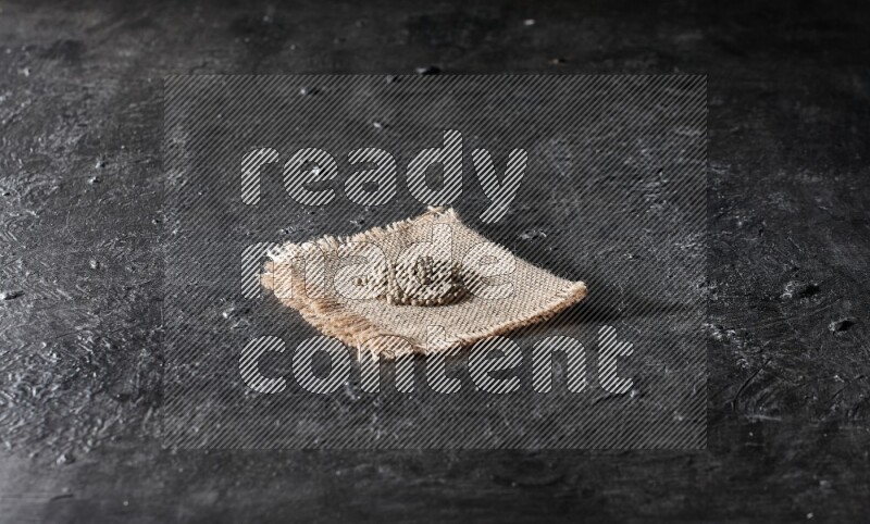 White pepper beads on a burlap piece of fabric on textured black flooring