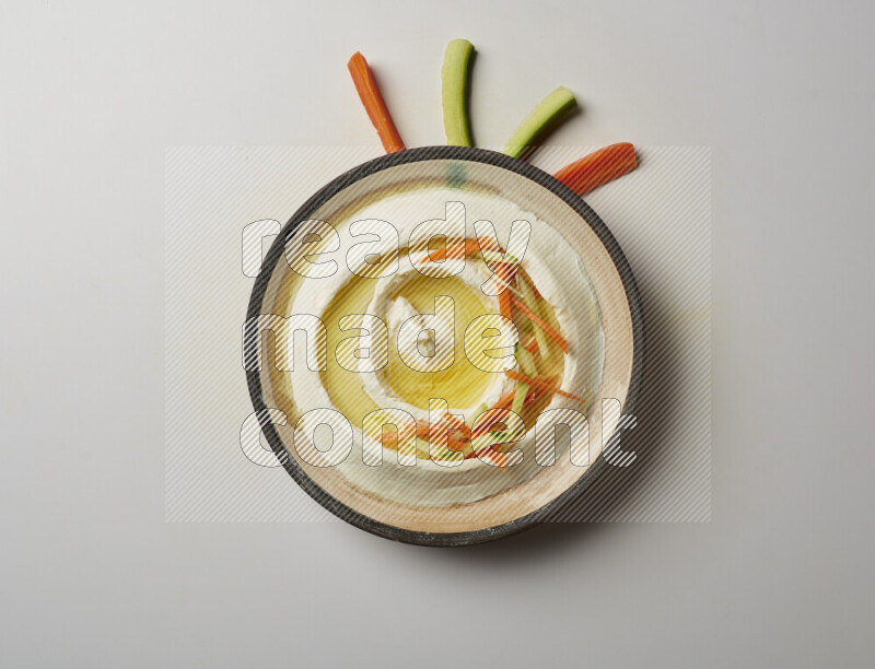 Lebnah garnished with sliced carrots &cucumber in a pottery plate on a white background