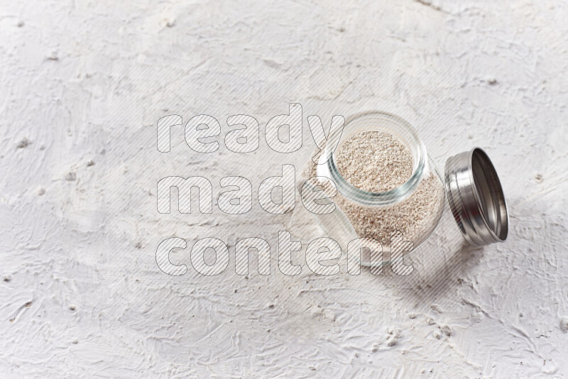 A glass jar full of onion powder on white background