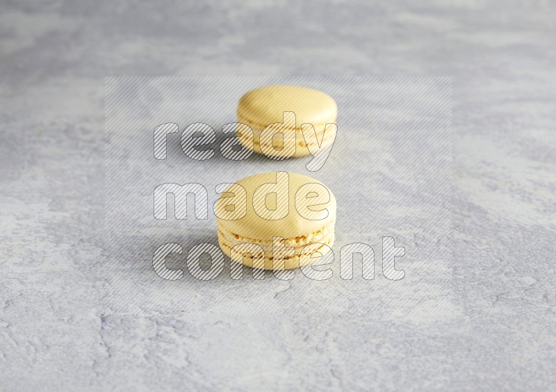45º Shot of two Yellow Vanilla macarons  on white  marble background