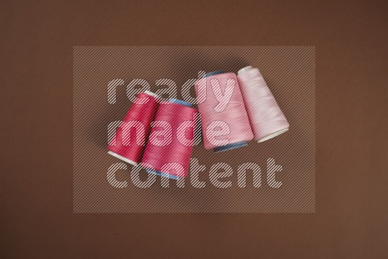 A pink collection of sewing and tailoring tools arranged on a brown background