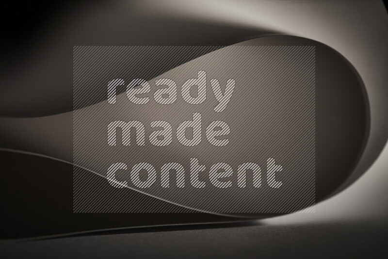 An abstract art piece displaying smooth curves in grey gradients created by colored light