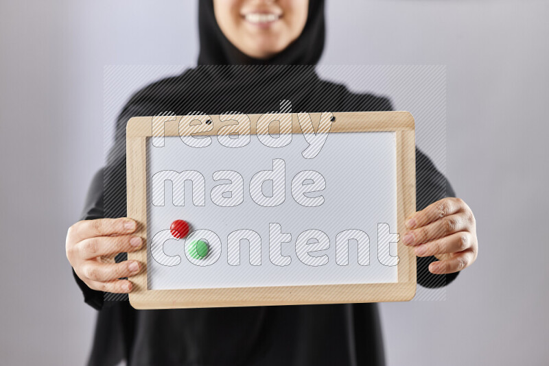 A woman in abaya holding books and a board in different positions (back to school)