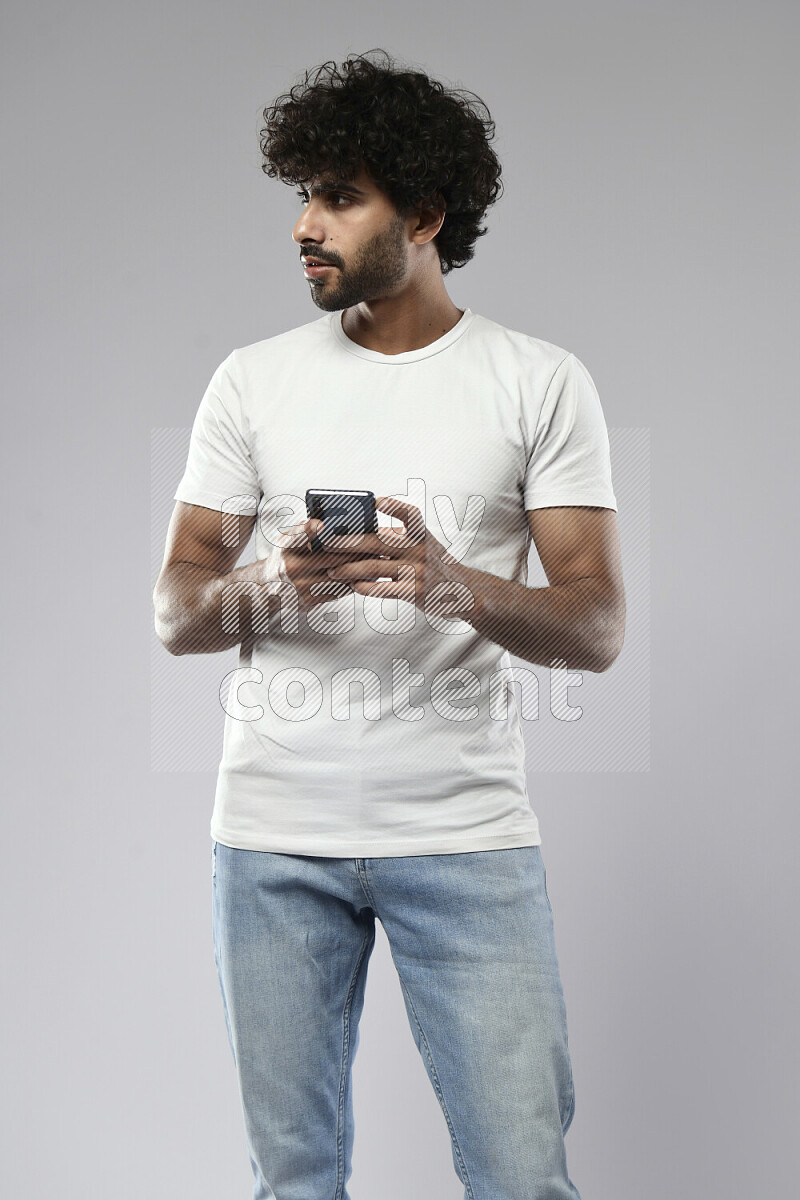 رجل يرتدي ملابس كاجوال يرسل رسائل نصية علي الهاتف علي خلفية بيضاء