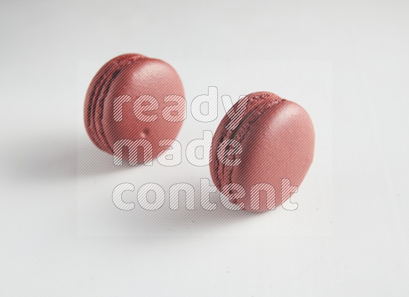 45º Shot of two Red Velvet macarons on white background