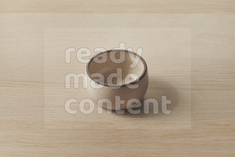 A beige pottery oven bowl on light wooden background