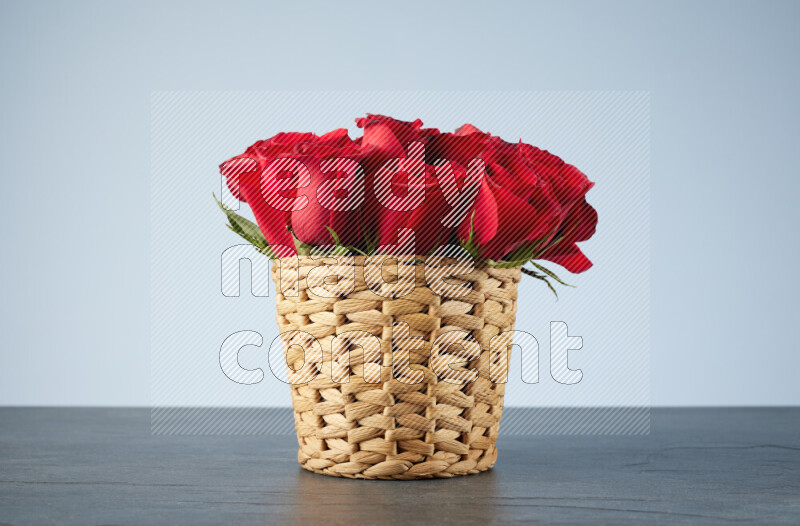 Vibrant red roses in a wicker basket on black marble background
