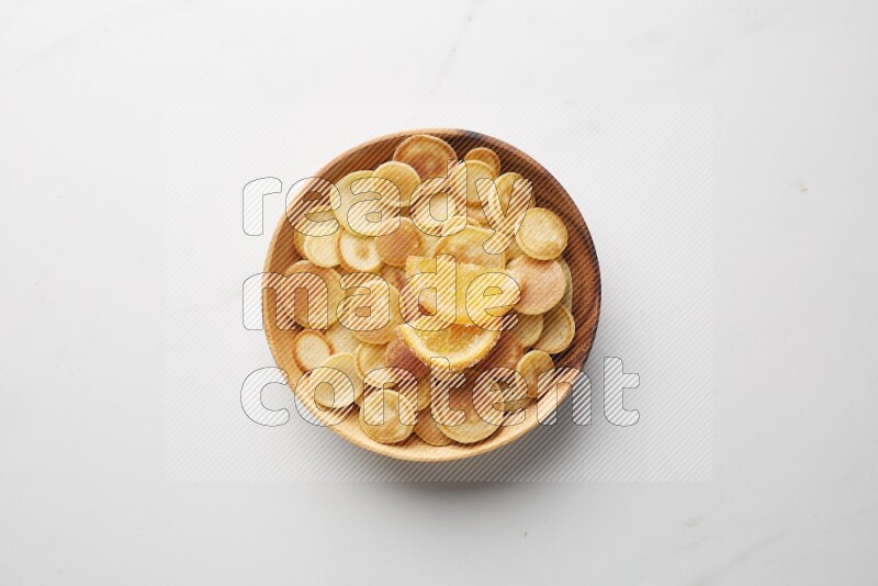 Top-view shot of orange candy cereal pancakes in a round bowl on white background
