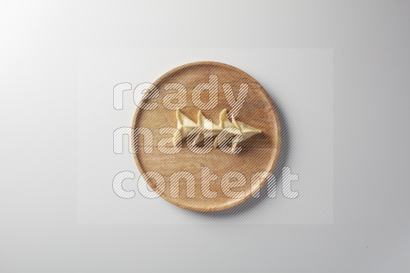 Four Sambosas on a wooden round plate on a white background