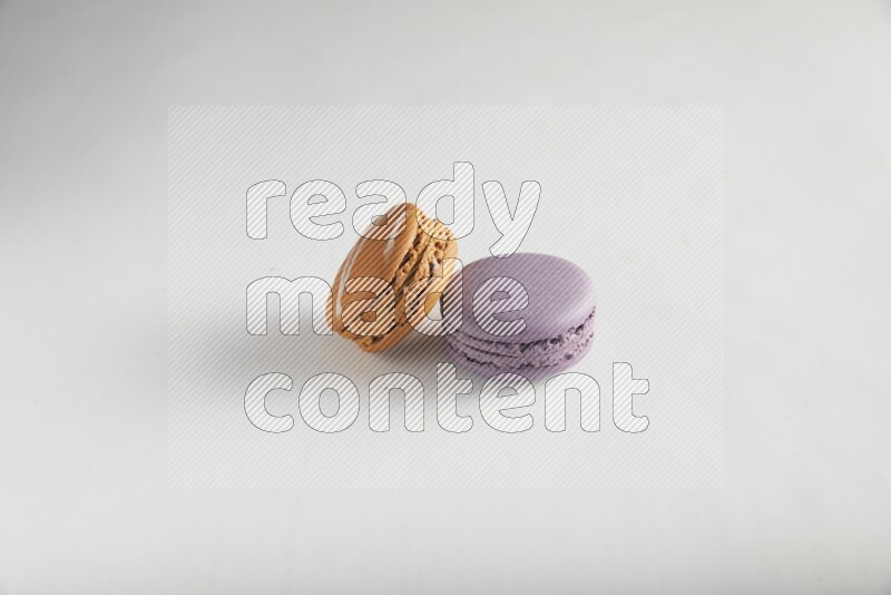 45º Shot of of two assorted Brown Irish Cream, and Purple Blueberry macarons on white background