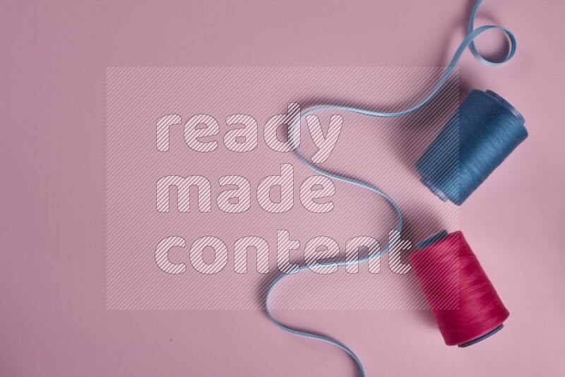A blue collection of sewing and tailoring tools arranged on a pink background