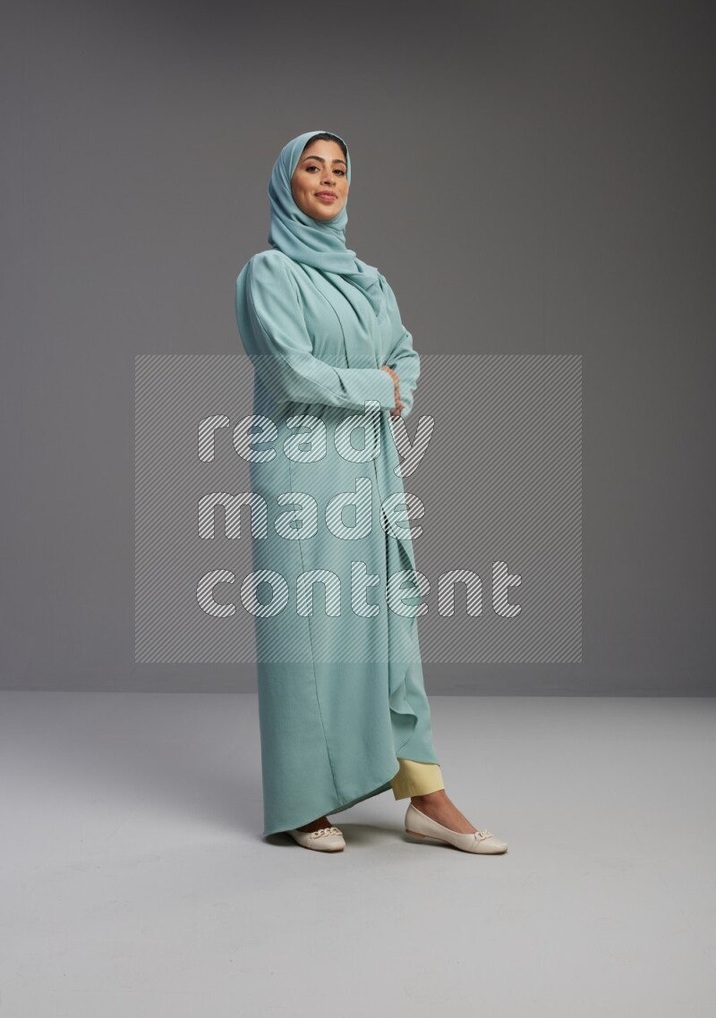 Saudi Woman wearing Abaya standing interacting with the camera on Gray background