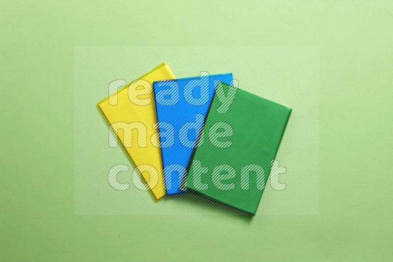 Multicolored notebooks on green background (back to school)