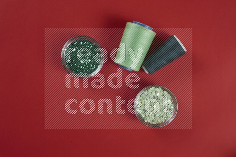 مجموعة من أدوات الخياطة والتفصيل خضراء وحمراء اللون على خلفية حمراء