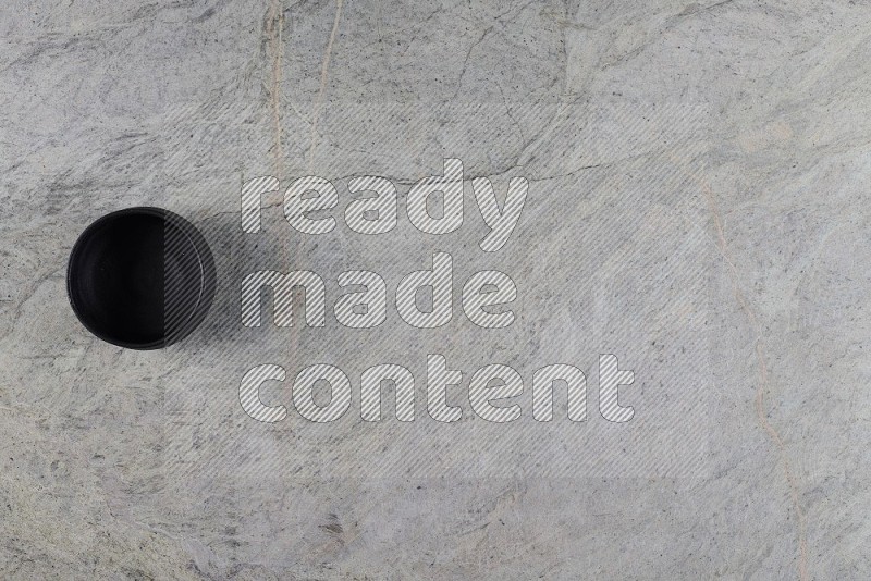 Top View Shot Of A Black Pottery Bowl On Grey Marble Flooring