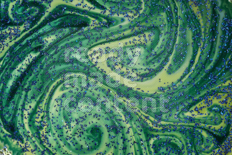 A close-up of sparkling blue glitter scattered on swirling blue and green background