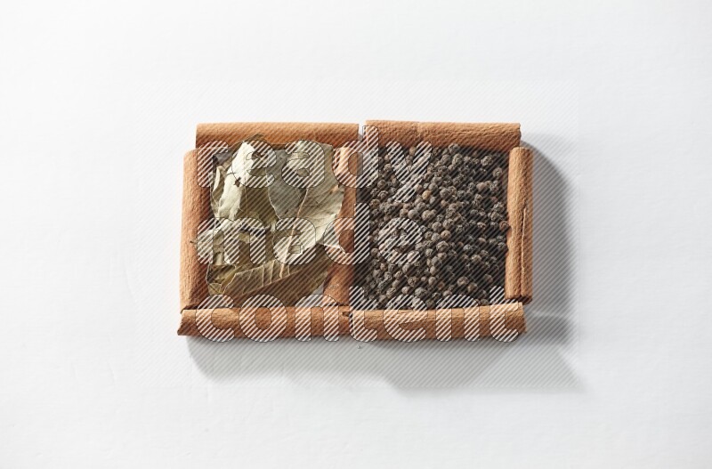2 squares of cinnamon sticks full of black peppers and bay laurel leaves on white flooring