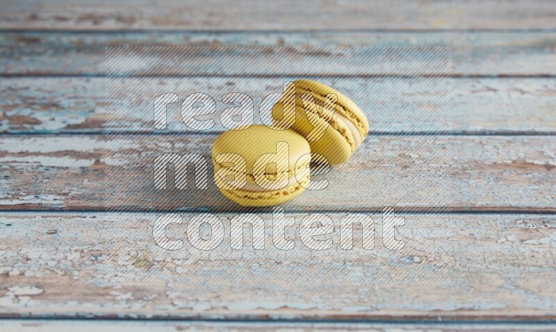 45º Shot of two Yellow Lime macarons on light blue wooden background