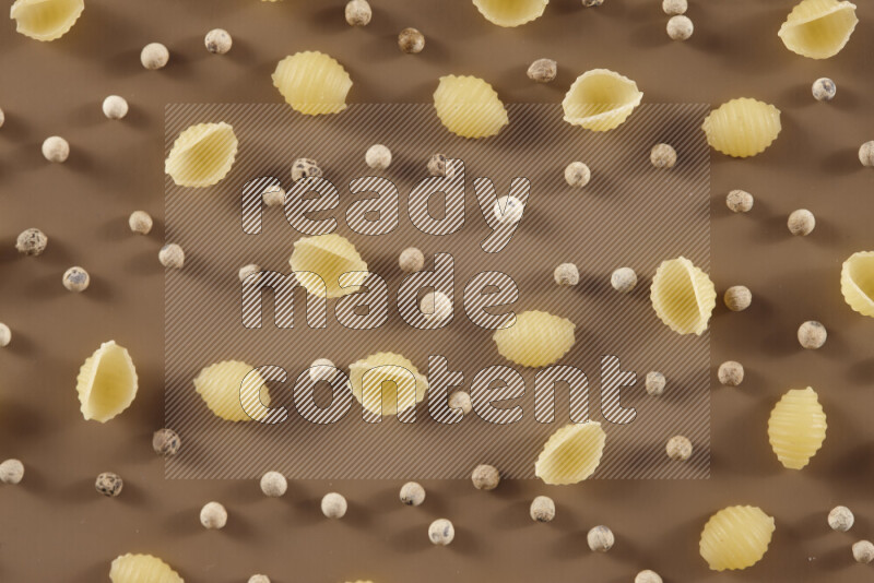 معكرونة مع مكونات متنوعة من الطماطم والثوم والبصل والفلفل الأحمر والفلفل الأسود والفلفل الأبيض وأوراق الغار وإكليل الجبل والهيل على خلفية بيج