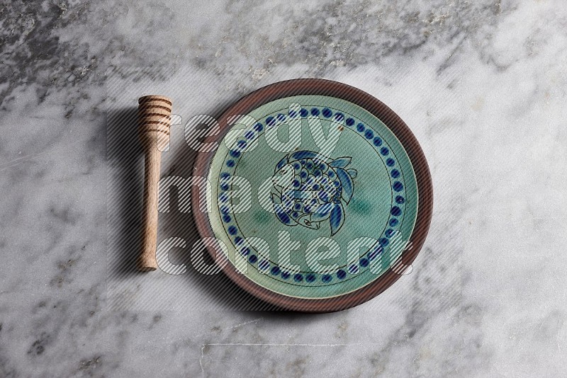 Decorative Pottery Plate with wooden honey handle on the side with grey marble flooring, 65 degree angle