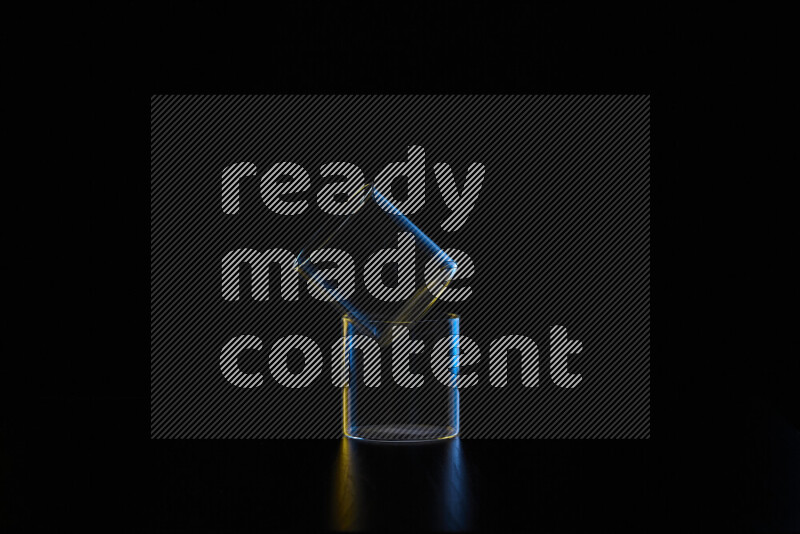 Glassware with rim light in blue and yellow against black background