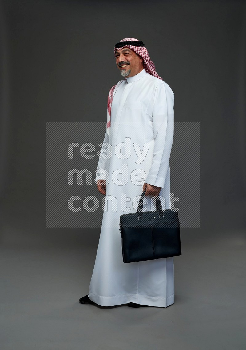 Saudi man with shomag Standing holding bag on gray background