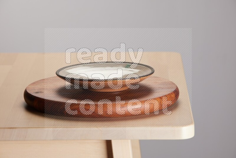 multi-colored pottery Plate placed on a dark colored wooden tray on the edge of wooden table