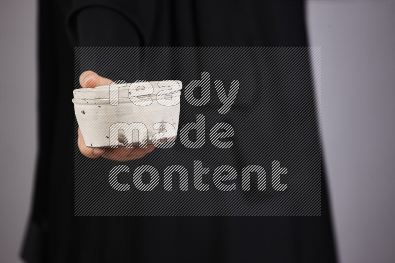 A woman in black abaya holding different pottery essentials in different positions