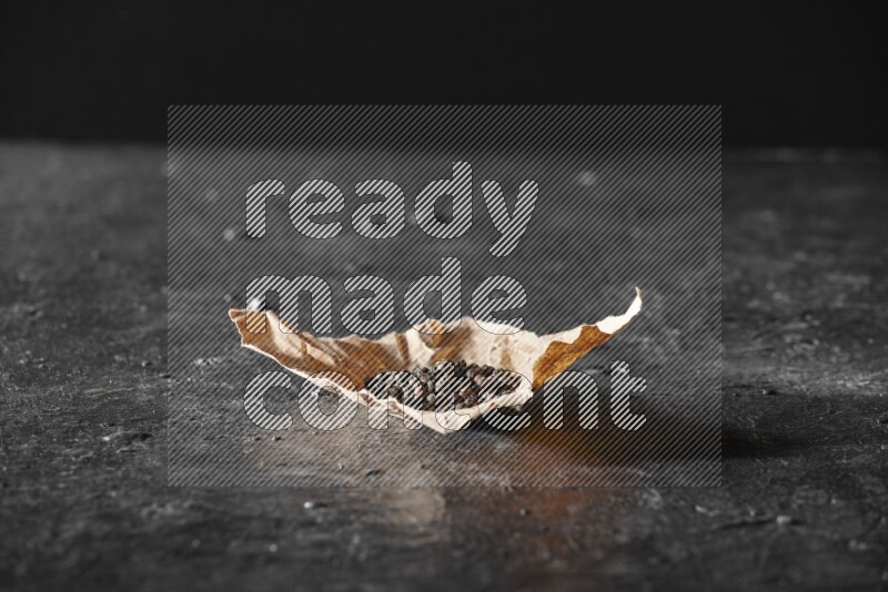 Black pepper beads on crumpled paper on a textured black flooring