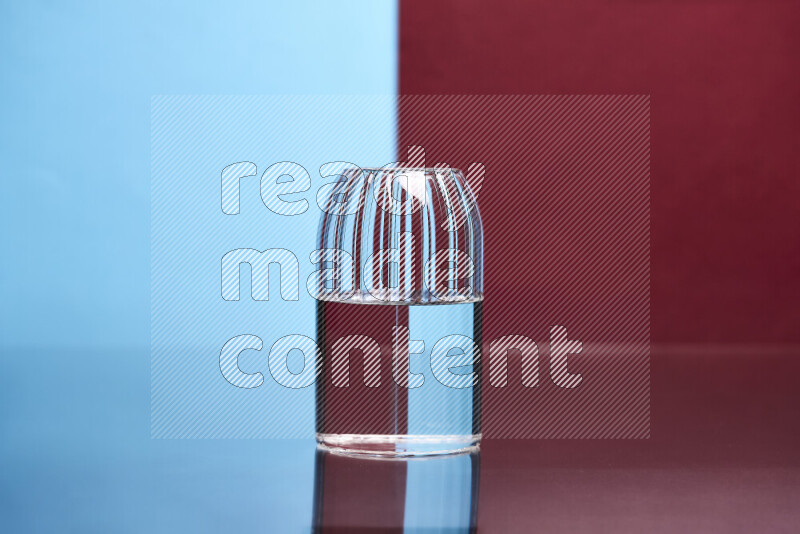 The image features a clear glassware filled with water, set against light blue and dark red background