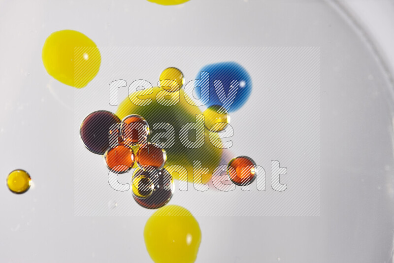 Close-ups of abstract red, blue, yellow and green watercolor drops on oil Surface on white background