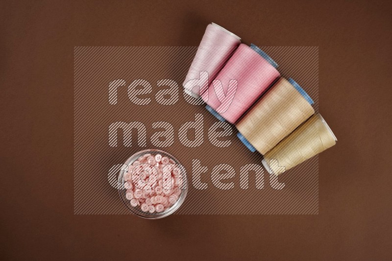 Pink sewing supplies on brown background