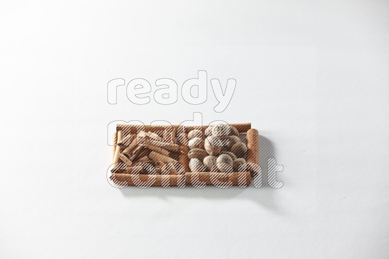 مربعان من أعواد القرفة ممتلئان بقطع من القرفة وجوزة الطيب علي خلفية بيضاء