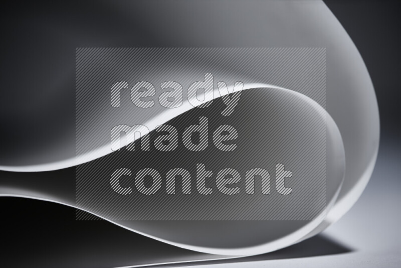 An abstract art piece displaying smooth curves in grey gradients created by colored light