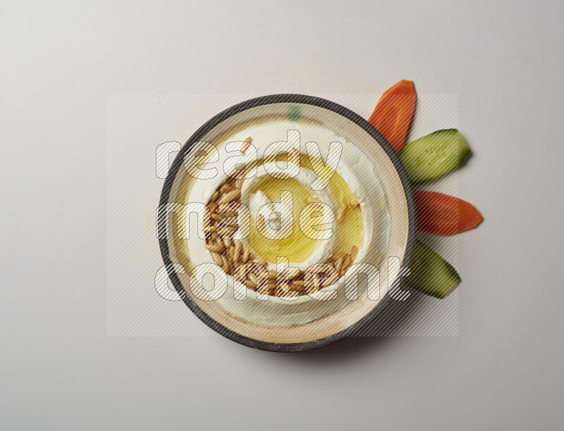 Lebnah garnished with pine nuts in a pottery plate on a white background