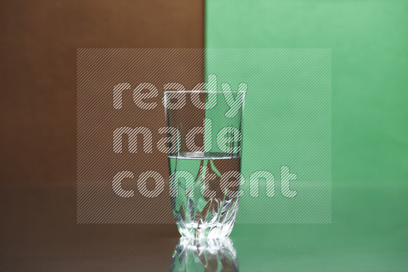 The image features a clear glassware filled with water, set against brown and green background